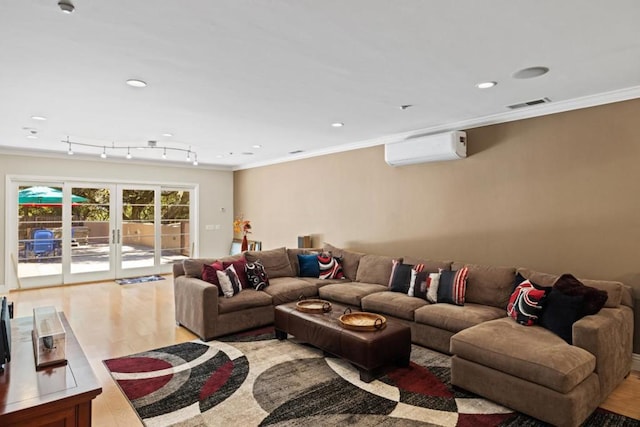 living room featuring french doors, rail lighting, a wall mounted air conditioner, crown molding, and light hardwood / wood-style floors