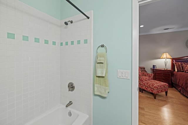 bathroom with hardwood / wood-style floors, tiled shower / bath combo, and ornamental molding