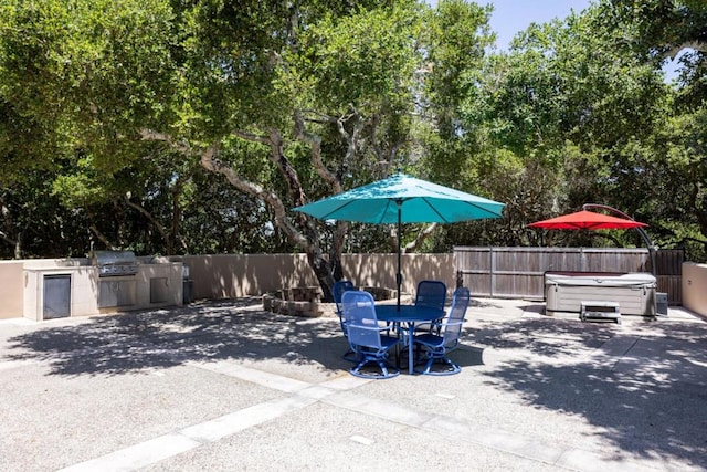 view of patio / terrace with grilling area, an outdoor kitchen, and a hot tub