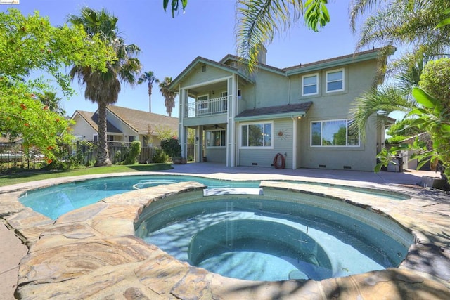 back of house featuring a pool with hot tub and a balcony