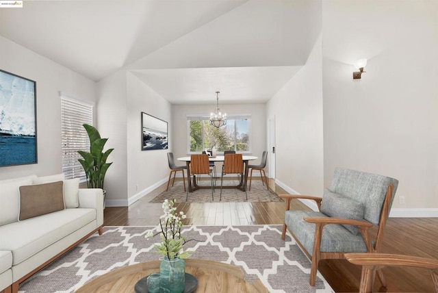 living room featuring hardwood / wood-style flooring, lofted ceiling, and a chandelier