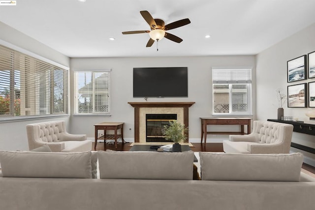 living room featuring ceiling fan, a tiled fireplace, and wood-type flooring