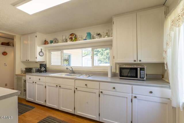 kitchen with sink, white cabinetry, and wood-type flooring