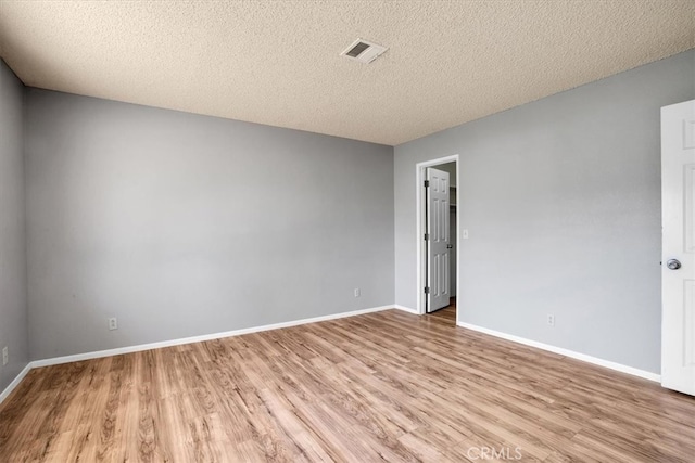 empty room featuring a textured ceiling and light hardwood / wood-style flooring