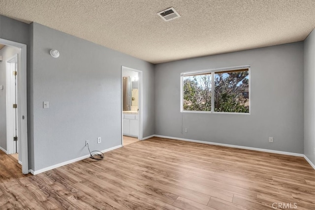 interior space featuring light hardwood / wood-style flooring, ensuite bath, and a textured ceiling