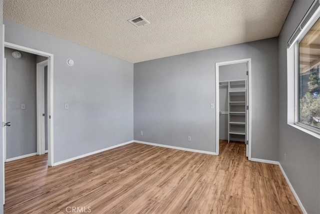 spare room featuring a textured ceiling and light hardwood / wood-style floors