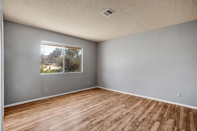 unfurnished room featuring a textured ceiling and light wood-type flooring