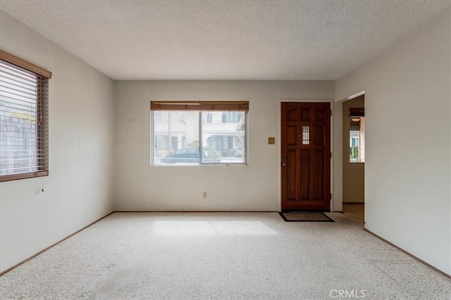 unfurnished room with a wealth of natural light, light carpet, and a textured ceiling