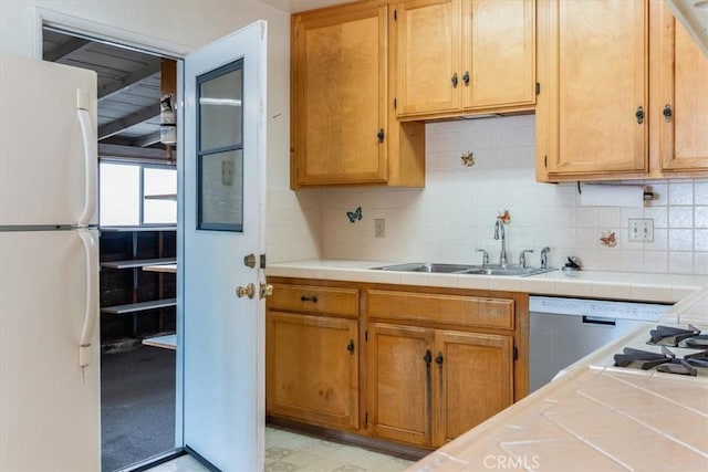 kitchen with tile countertops, white fridge, tasteful backsplash, and sink