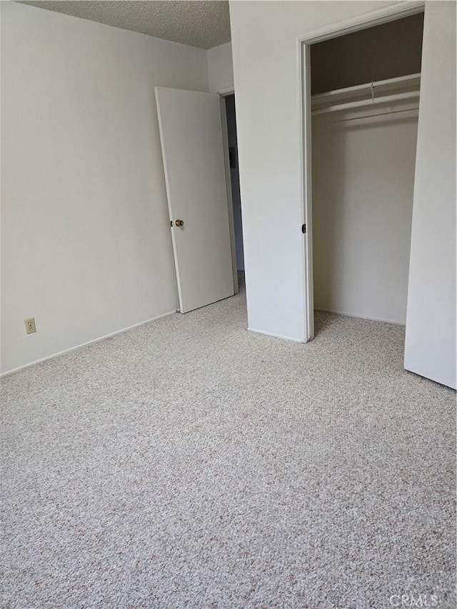 unfurnished bedroom with a closet, light colored carpet, and a textured ceiling