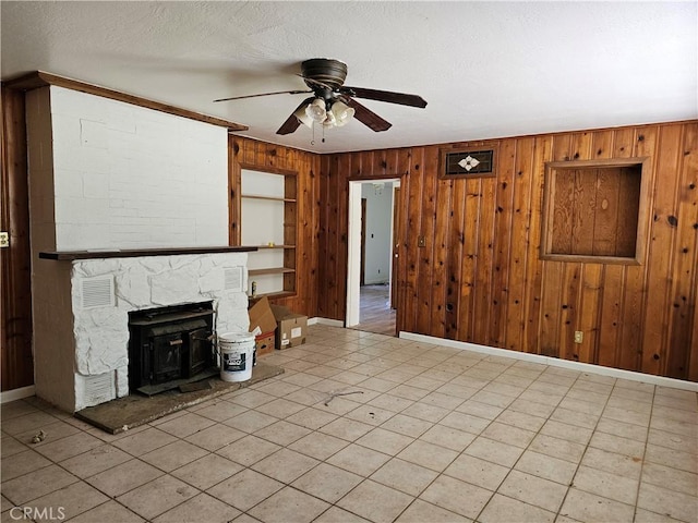 unfurnished living room featuring ceiling fan, a wood stove, and wooden walls