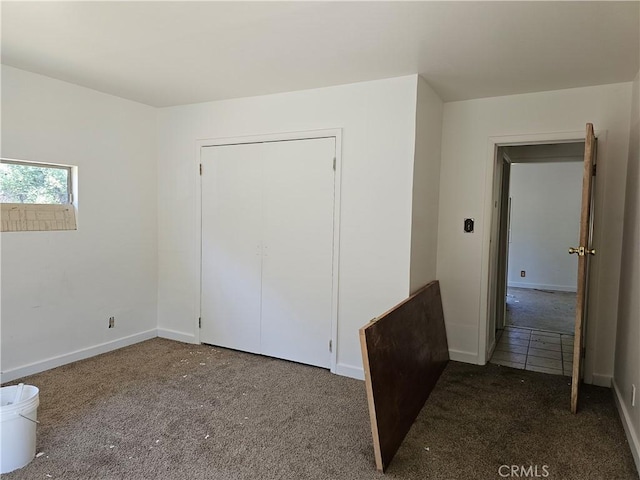 unfurnished bedroom with dark carpet and a closet