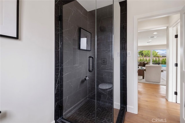 bathroom with hardwood / wood-style floors and a shower with shower door