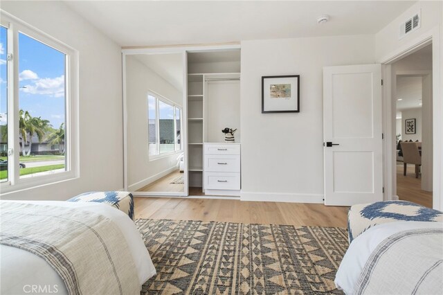 bedroom featuring a closet, light wood-type flooring, and multiple windows