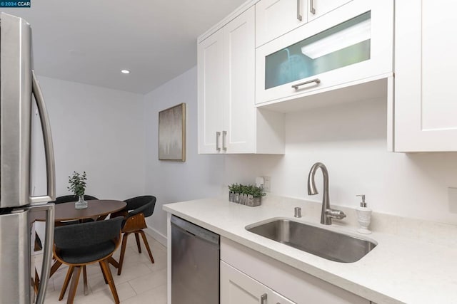 kitchen with light tile patterned flooring, appliances with stainless steel finishes, white cabinetry, and sink