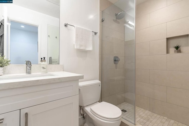 bathroom with tiled shower, vanity, and toilet