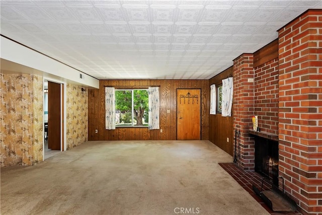 unfurnished living room with carpet flooring, wood walls, and a fireplace