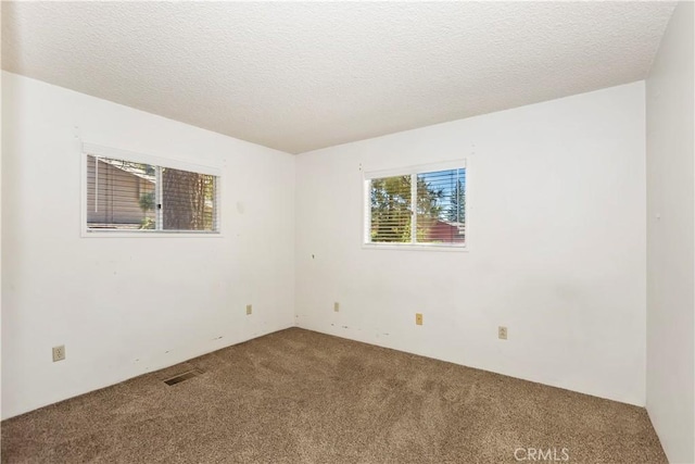 spare room featuring a textured ceiling and carpet