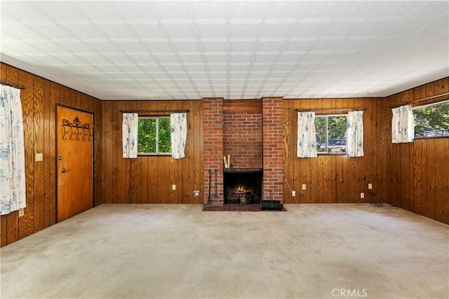 unfurnished living room with a fireplace, plenty of natural light, and wooden walls