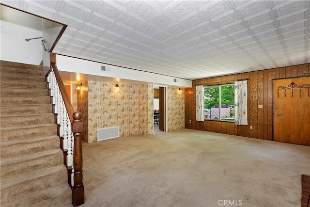 unfurnished living room with wooden walls and carpet floors