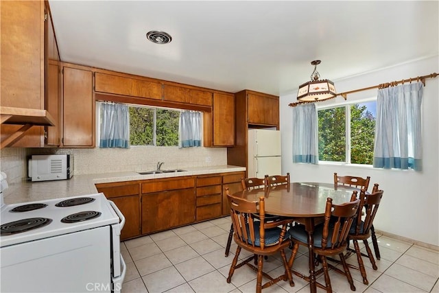 kitchen with decorative light fixtures, light tile patterned floors, sink, and white appliances