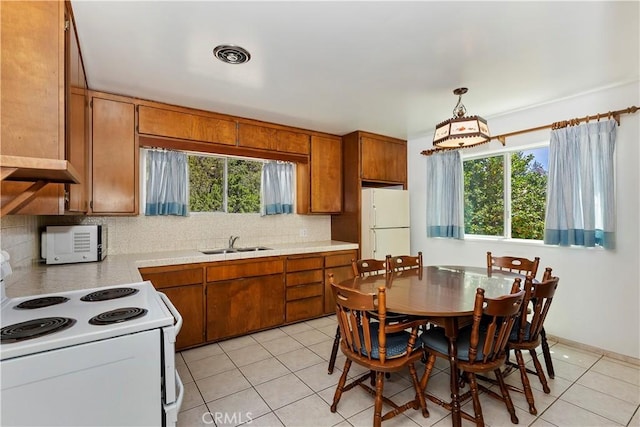 kitchen featuring sink, light tile patterned floors, pendant lighting, white appliances, and backsplash