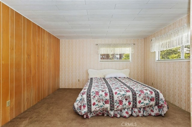 bedroom with carpet floors and wooden walls