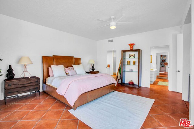 tiled bedroom with ceiling fan and ensuite bath