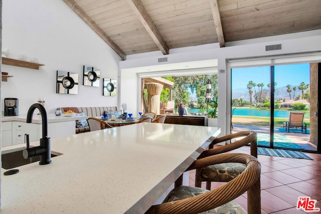 kitchen with a water view, wood ceiling, white cabinets, and vaulted ceiling with beams