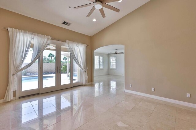 tiled empty room featuring high vaulted ceiling, ceiling fan, plenty of natural light, and french doors