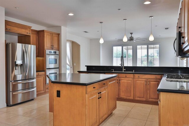 kitchen with appliances with stainless steel finishes, hanging light fixtures, a center island, and sink