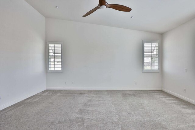 carpeted spare room featuring lofted ceiling and ceiling fan