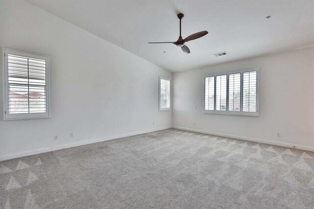 carpeted empty room featuring ceiling fan, plenty of natural light, and vaulted ceiling