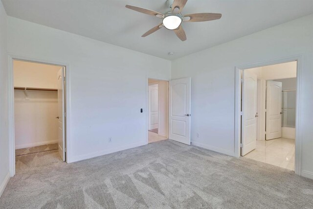 unfurnished bedroom featuring light colored carpet, ceiling fan, and a walk in closet