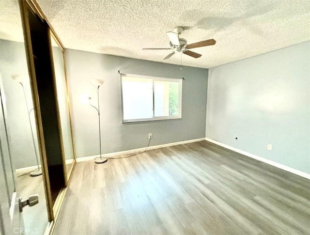 spare room with a textured ceiling, wood-type flooring, and ceiling fan