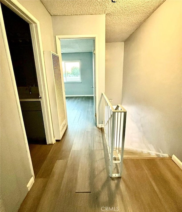 hallway featuring wood-type flooring and a textured ceiling