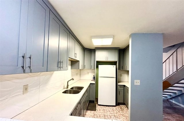 kitchen featuring gray cabinetry, sink, backsplash, and white refrigerator