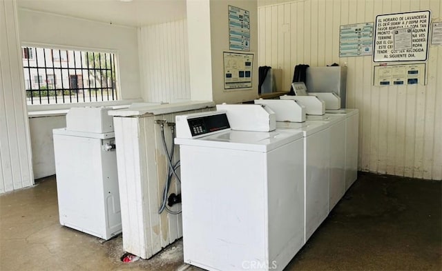 clothes washing area with washer and dryer and wood walls