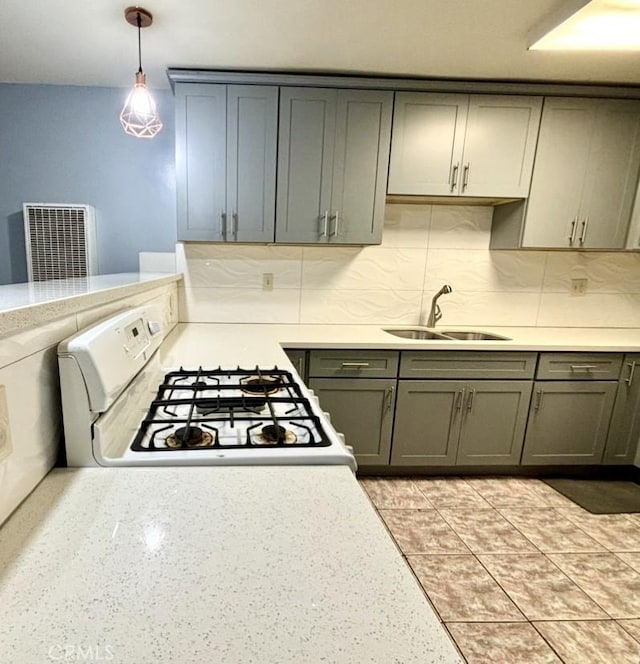 kitchen featuring hanging light fixtures, sink, white range with gas stovetop, and gray cabinetry