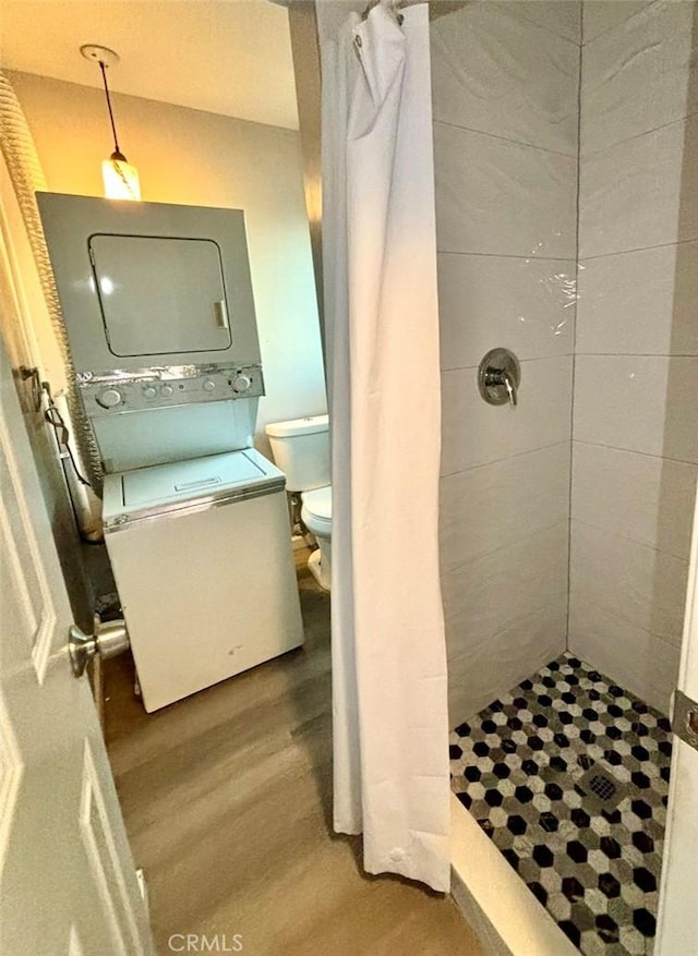 bathroom featuring hardwood / wood-style floors, stacked washing maching and dryer, curtained shower, and toilet