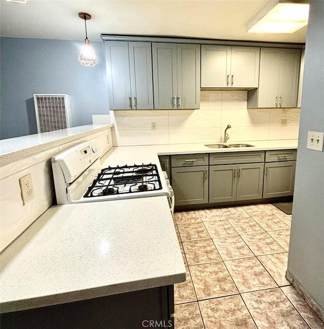 kitchen featuring sink, white range with gas stovetop, decorative light fixtures, light tile patterned floors, and backsplash