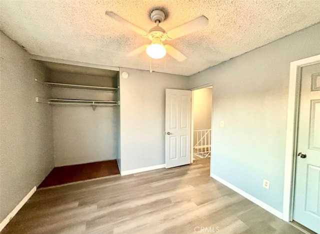 unfurnished bedroom featuring ceiling fan, a textured ceiling, a closet, and light wood-type flooring