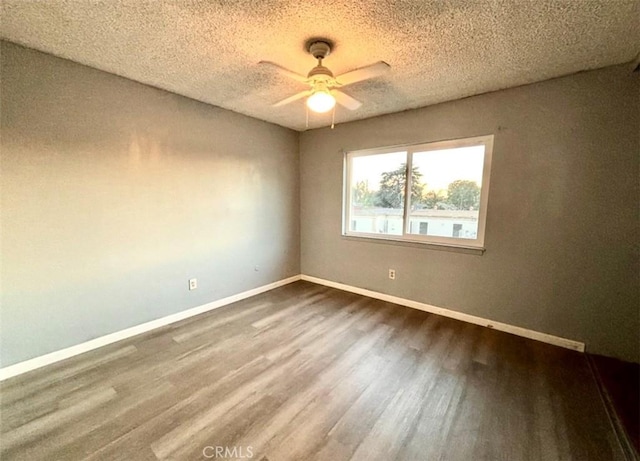 empty room with a textured ceiling, dark wood-type flooring, and ceiling fan