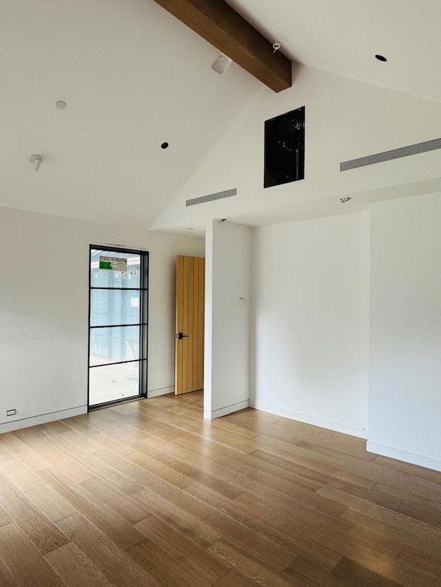 spare room with beam ceiling, high vaulted ceiling, and light hardwood / wood-style flooring