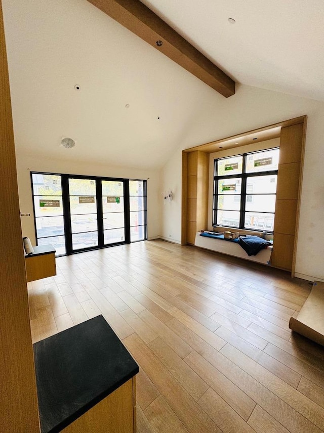 interior space with beam ceiling, high vaulted ceiling, and light wood-type flooring