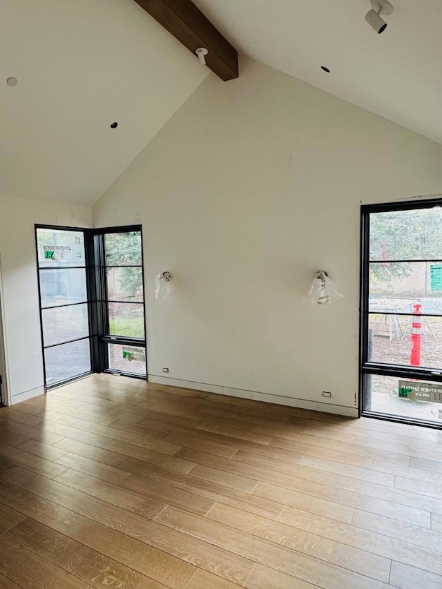 empty room with beamed ceiling, high vaulted ceiling, and light hardwood / wood-style flooring