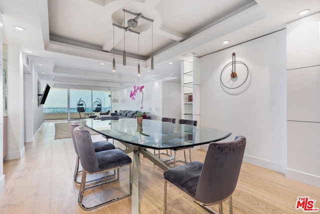 dining area with a tray ceiling, expansive windows, and light hardwood / wood-style flooring