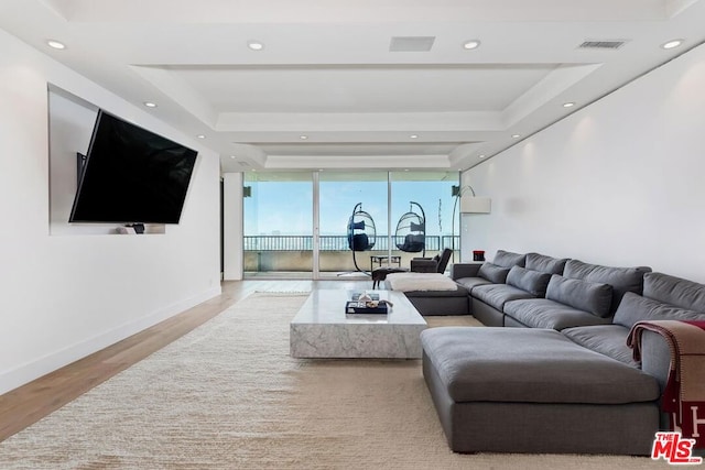 living room featuring floor to ceiling windows, light hardwood / wood-style flooring, and a tray ceiling