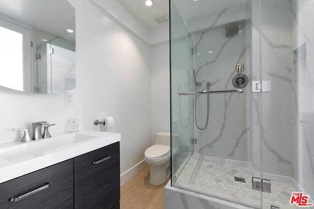 bathroom featuring toilet, vanity, an enclosed shower, and hardwood / wood-style floors