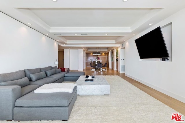 living room with a tray ceiling and hardwood / wood-style floors